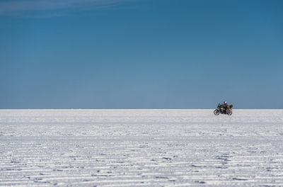 Man riding his touring motorbike on the salt flats of uyuni in bolivia