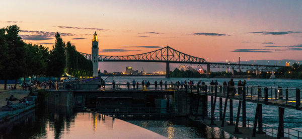 Bridge over calm river against sky during sunset