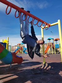 Portrait of man hanging on monkey bars at playground