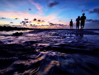 Silhouette people on beach against sky during sunset