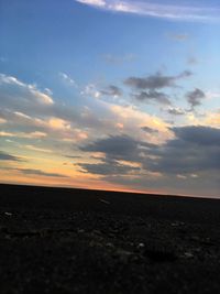 Scenic view of landscape against cloudy sky during sunset