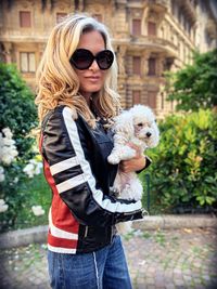 Portrait of woman carrying dog in city