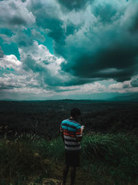 Rear view of man standing on field against sky