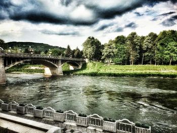 Bridge over river against cloudy sky