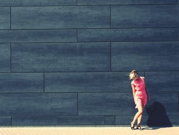 Rear view of woman walking against wall