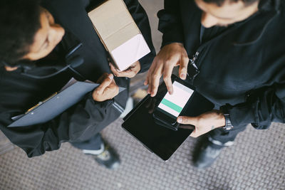 High angle view of female and male colleagues using mobile phone at distribution warehouse