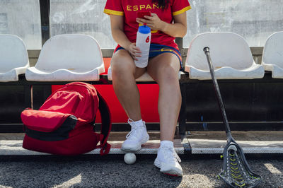 Player using smart phone sitting on seat at dugout