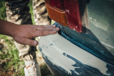 Cropped hand of man on car in garage