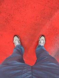 Low section of man standing on red shoes