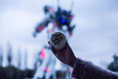 Close-up of hand holding leaf against sky