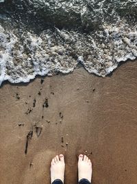 Low section of person standing on shore at beach