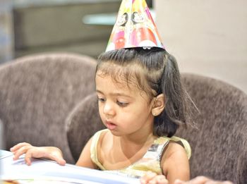 Cute girl wearing party hat sitting at home