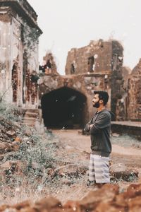 Side view of man standing against old ruins