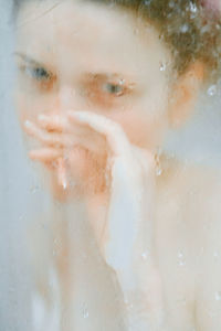 Close-up of woman seen through wet glass