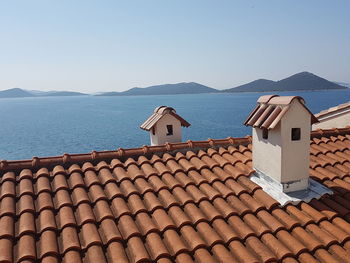 Air ducts on house roof by sea against clear sky