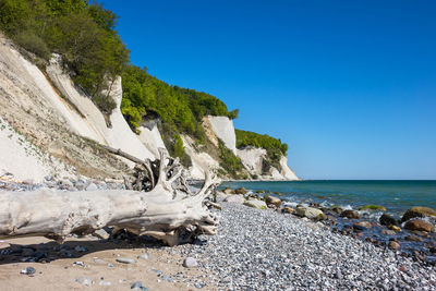 Scenic view of beach amidst mountain against clear blue sky during sunny day