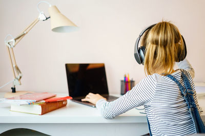 Midsection of woman using phone while sitting on table