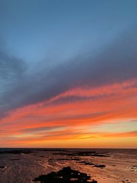 Scenic view of sea against dramatic sky during sunset