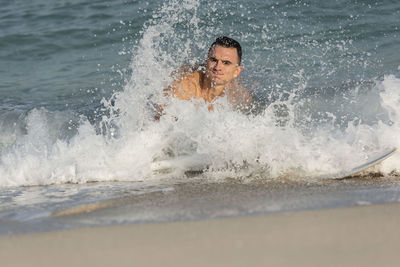 Portrait of man splashing water in sea