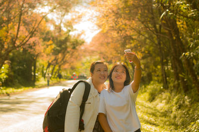 Portrait of smiling young woman standing against trees