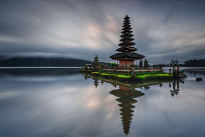 Traditional building against sky with lake in background