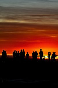 Silhouette people against orange sky