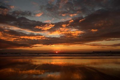 Scenic view of sea against cloudy sky during sunset