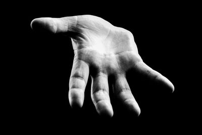 Cropped image of human hand against black background