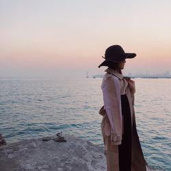 Rear view of woman standing by sea against clear sky