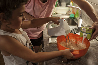 Rear view of people standing in kitchen at home