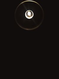 Low angle view of illuminated light bulb against black background