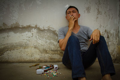 Mature man sitting by narcotics against wall