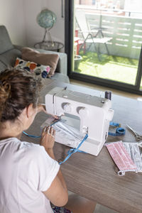 Woman making face masks with a sewing machine at home