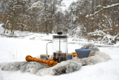 Drinking coffee or tea on the snow in winter with cups, warm blankets and winter landscape 