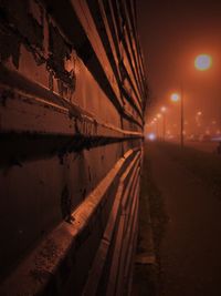 Road by illuminated street against sky at night