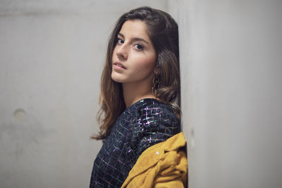 Portrait of beautiful young woman standing against wall