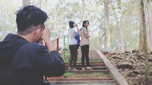 Side view of couple standing against trees