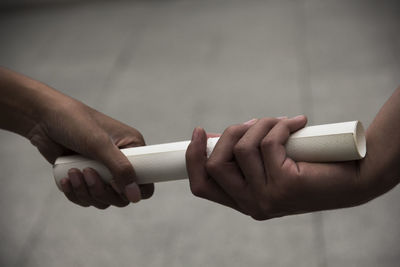 Close-up of hands holding rolled paper