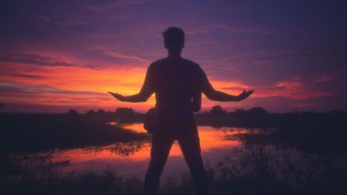 Silhouette man standing by sea against sky during sunset