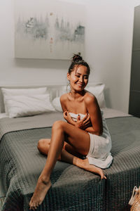 Young woman sitting on bed at home