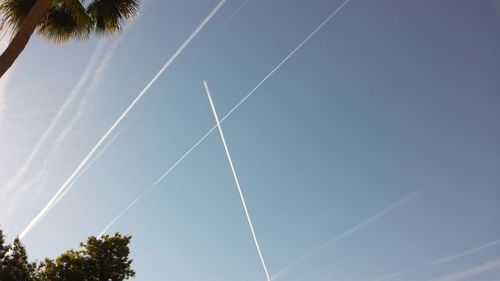 Low angle view of vapor trails against blue sky