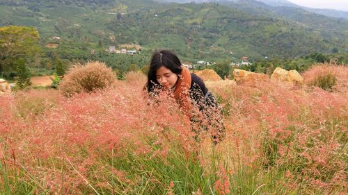 Woman amidst flowering plants on field