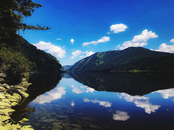 Scenic view of lake and mountains against blue sky