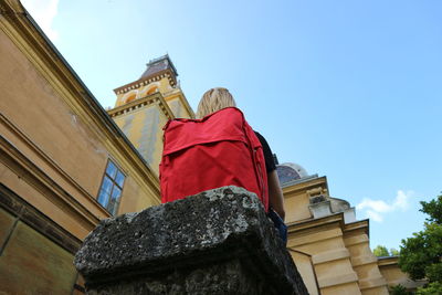 Low angle view of woman sitting on rock by castle