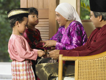 Grandchildren giving greeting cards to grandparents at home