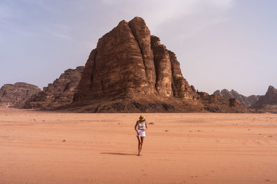 Rear view of man standing at desert against sky