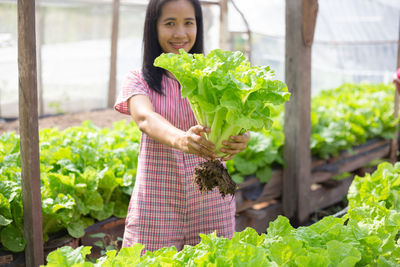 Portrait of smiling woman holding plant