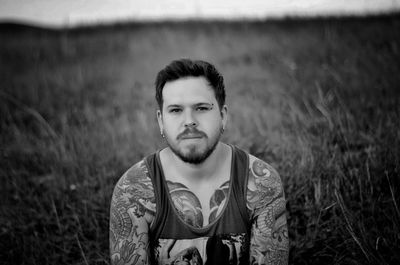 Portrait of tattooed young man standing on land