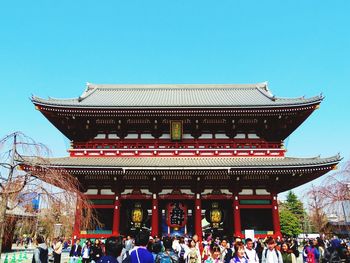 Group of people in front of building against clear sky