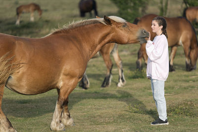 Girl with horse standing on field